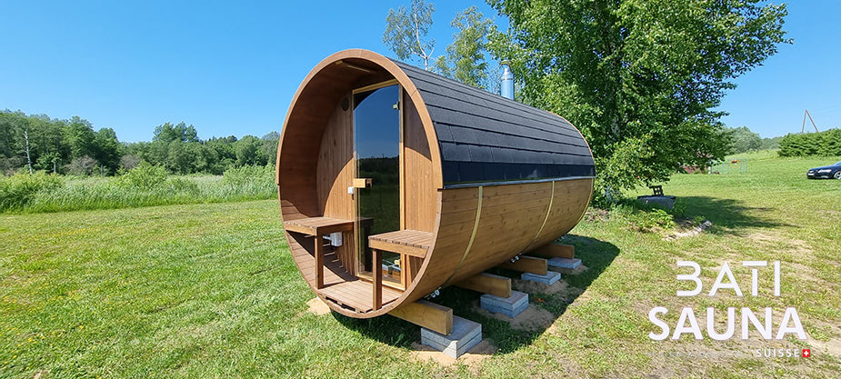 Sauna tonneau posé sur des dalles de béton dans le gazon